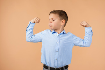 little boy shows his biceps on beige background. child showing his muscles