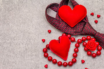 Fototapeta premium Valentines Day concept. Red felt hearts, women beads, men tie. Stone concrete background