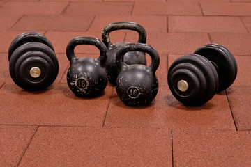 Naklejka na ściany i meble Dumbbells and kettlebells on a floor. Bodybuilding equipment. Fitness or bodybuilding concept background.