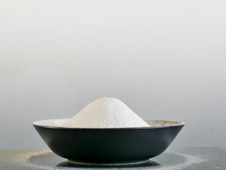 White flour on a black bowl. Spilled flour.