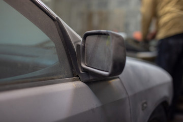 Dirty car in the dust, distant view mirror