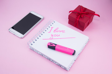 The gift and the smartphone are on a pink background. A gift for a woman. The marker inscription I love you Stylized female flatly.