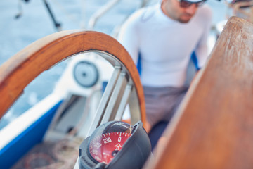 Sailor using wheel to steer rudder on a sailing boat.