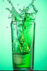 splash in a glass with a green tarragon carbonated drink from falling ice