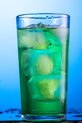 misted glass with green carbonated drink tarragon and cubes of real ice