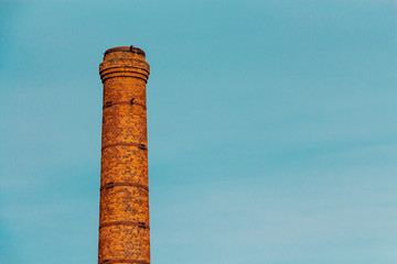 Old brick chimney. Blue sky, cloud haze
