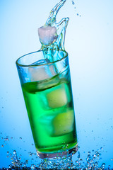 splash in a glass with a green tarragon carbonated drink from falling ice