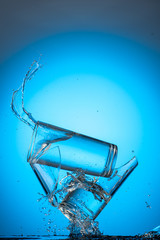 two tall glasses of liquid are broken into pieces and the contents are poured