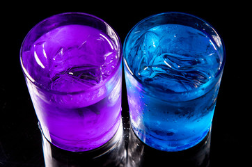 cold water with ice in a blue glass on a black background