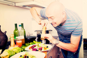 male prepares two salads and fills them with pepper