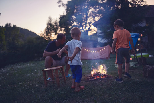 Father with children making a camping fire in the backyard.