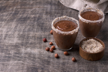 Chocolate mousse with cream and hazelnuts in glasses on old dark wooden table	