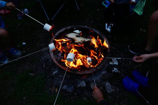 High Angle View Of People Roasting Marshmallows On Fire Pit At Campsite