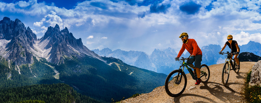 Cycling woman and man riding on bikes in Dolomites mountains andscape. Couple cycling MTB enduro trail track. Outdoor sport activity. © Gorilla
