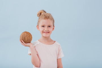 girl with coconut in hand. isolated on blue background, copy space, in studio - obrazy, fototapety, plakaty