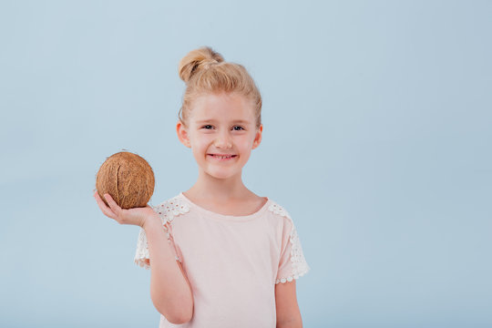 girl with coconut in hand. isolated on blue background, copy space, in studio
