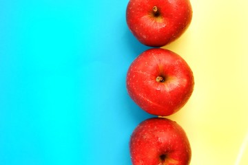 Red apple on a blue and yellow background. Apples top view. Place for text.
