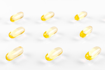 yellow omega capsules on white background, abstract pattern