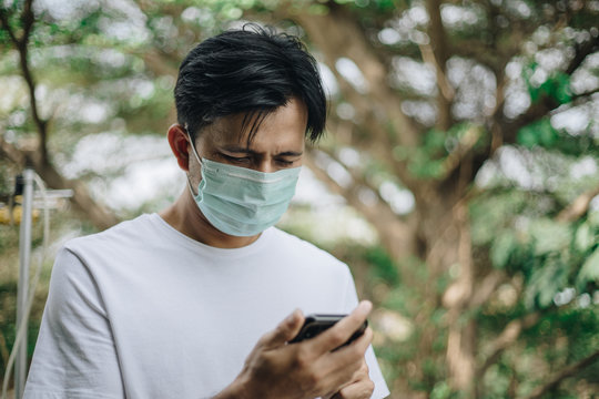 Young asian man use smartphone and wearing protective mask to protect against germs and air pollution, health care concept