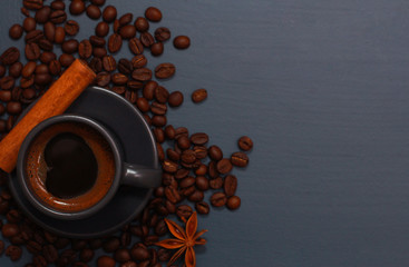 Dark grey cup of coffee, cinnamon and beans on blue table. Hot drink concept. Coffee shop, espresso, top view, copy space