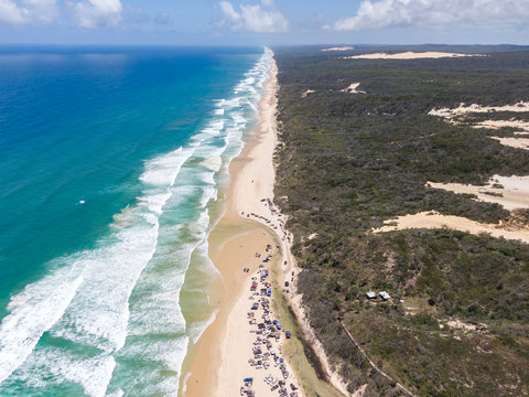 High angle aerial bird's eye drone view of four-wheel drive cars parked at Eli Creek, a river mouth with crystal clear water and popular tourist attraction on Fraser Island, Queensland, Australia.