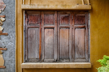 Fototapeta na wymiar Closed rustic wooden window outside old house cement wall.