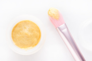 golden facial cream mask with a brush on white background, selective focus