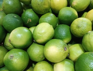  many beautiful green limes lie on the table