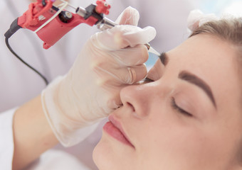 A young girl having red lips permanent makeup, micropigmentation