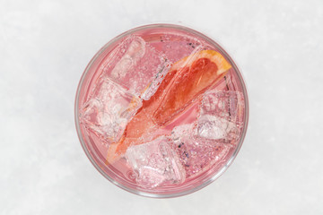 Pink gin tonic vodka soda fruit grapefruit cocktail drink in glass with ice, top view on white background