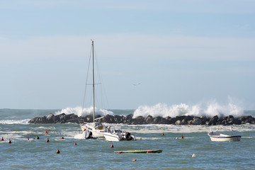 Fototapeta na wymiar Boats in a Port with Big Waves in Italy.