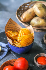 Photo of potato chips in a bowl with chili sauce on dark background. Chili ketchup. Ingredients. On a wooden table. Retro background. Front view. Studio photography. Image.