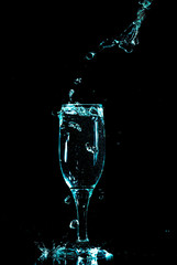 blue water with splashes in a glass on a black background