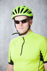 Portrait of an athlete cyclist on a light background in a helmet and a light green t-shirt.