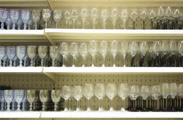 Many different gwinelasses for wine and shampagne on the shelves in store with place for prices