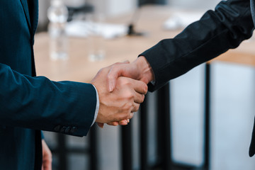 cropped view of businesswoman shaking hands with businessman