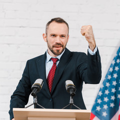 Naklejka premium selective focus of emotional speaker with clenched fist talking near microphones