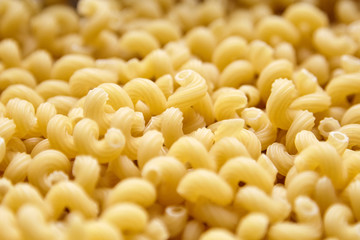 Cavatappi Pasta. Heap of uncooked macaroni, closeup. Italian cuisine, food Background
