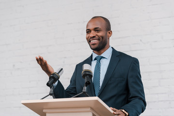 happy african american speaker gesturing near microphones