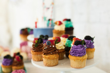 Sweets on the festive table.Holiday table with sweets, chocolate cupcakes with multi-colored toppings and colored cream