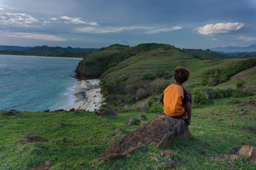 young man boy sitting on a rock beach