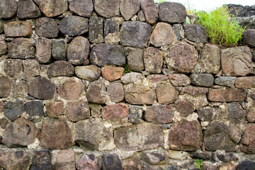 The stonework of the old ruined church. Masonry consists of large round stones. In some places on the wall has already begun to grow green grass.