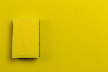 Yellow dishwasher sponge on a yellow background