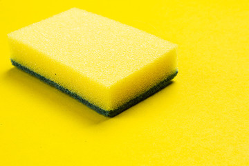 Yellow dishwasher sponge on a yellow background