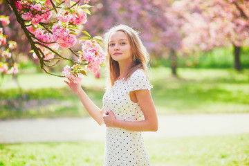 Young woman enjoying her walk in park during cherry blossom season on a nice spring day