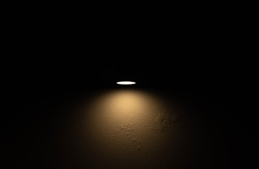 Dark old cement wall with little yellow light from bulb in the middle of wall.