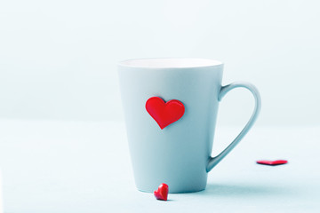 Blue cup with red hearts on turquoise background.