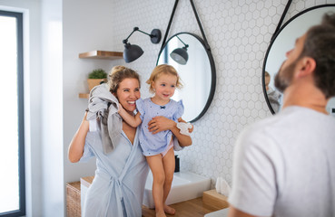 Young family with small daughter indoors in bathroom, talking.