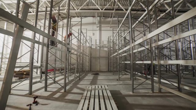 workers assemble metal racks in spacious plant warehouse