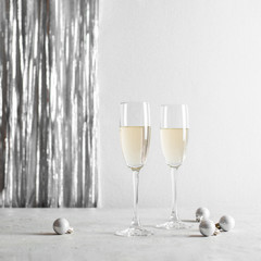 Two glasses with champange and christmas decorations on a silvery background